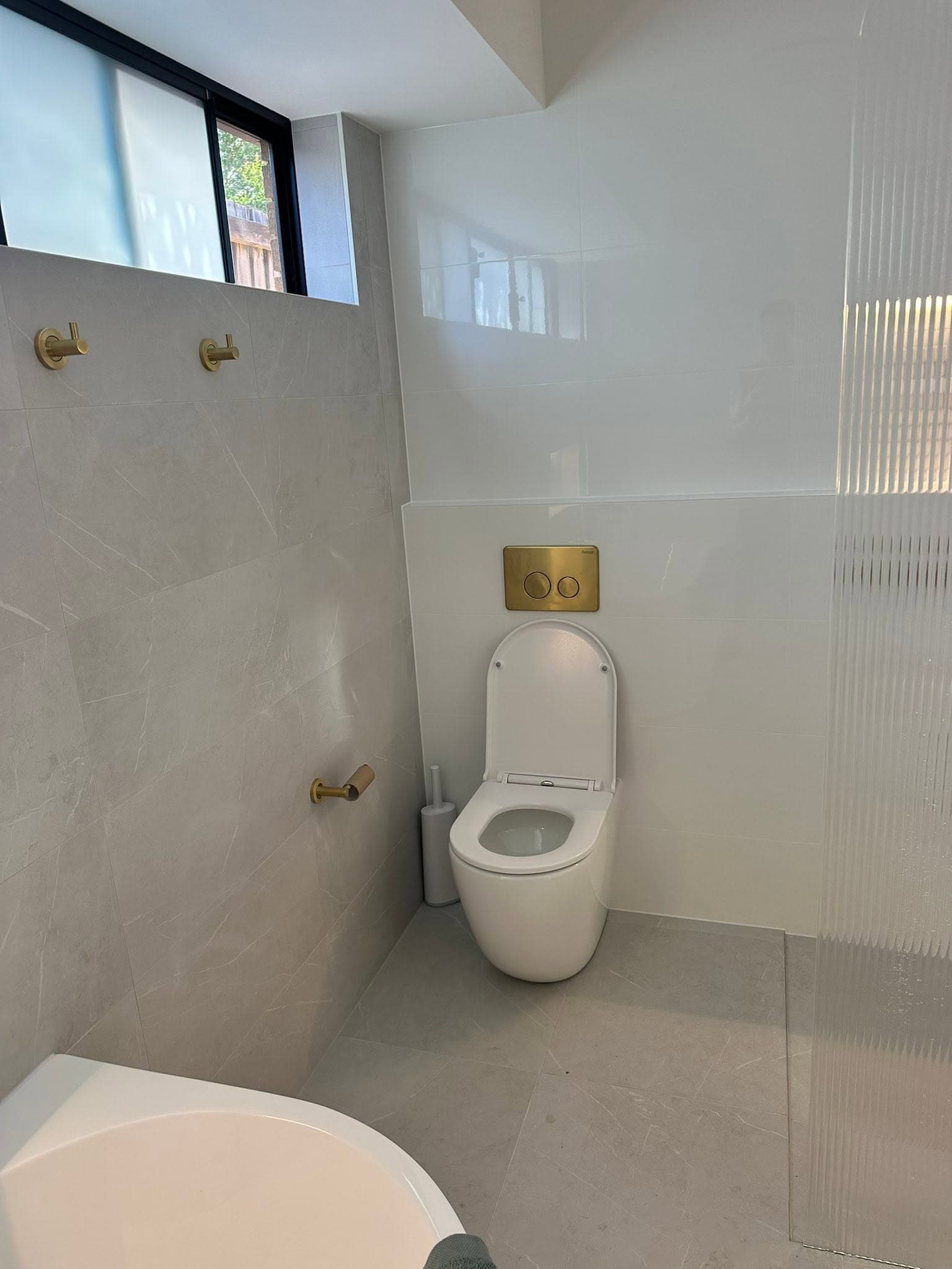 Wall-hung toilet with brushed brass fittings plumbed in during a bathroom renovation