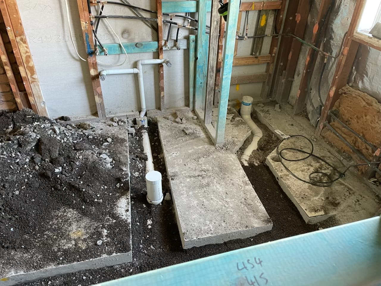 Drainage and supply pipework roughed in under a slab during a renovation