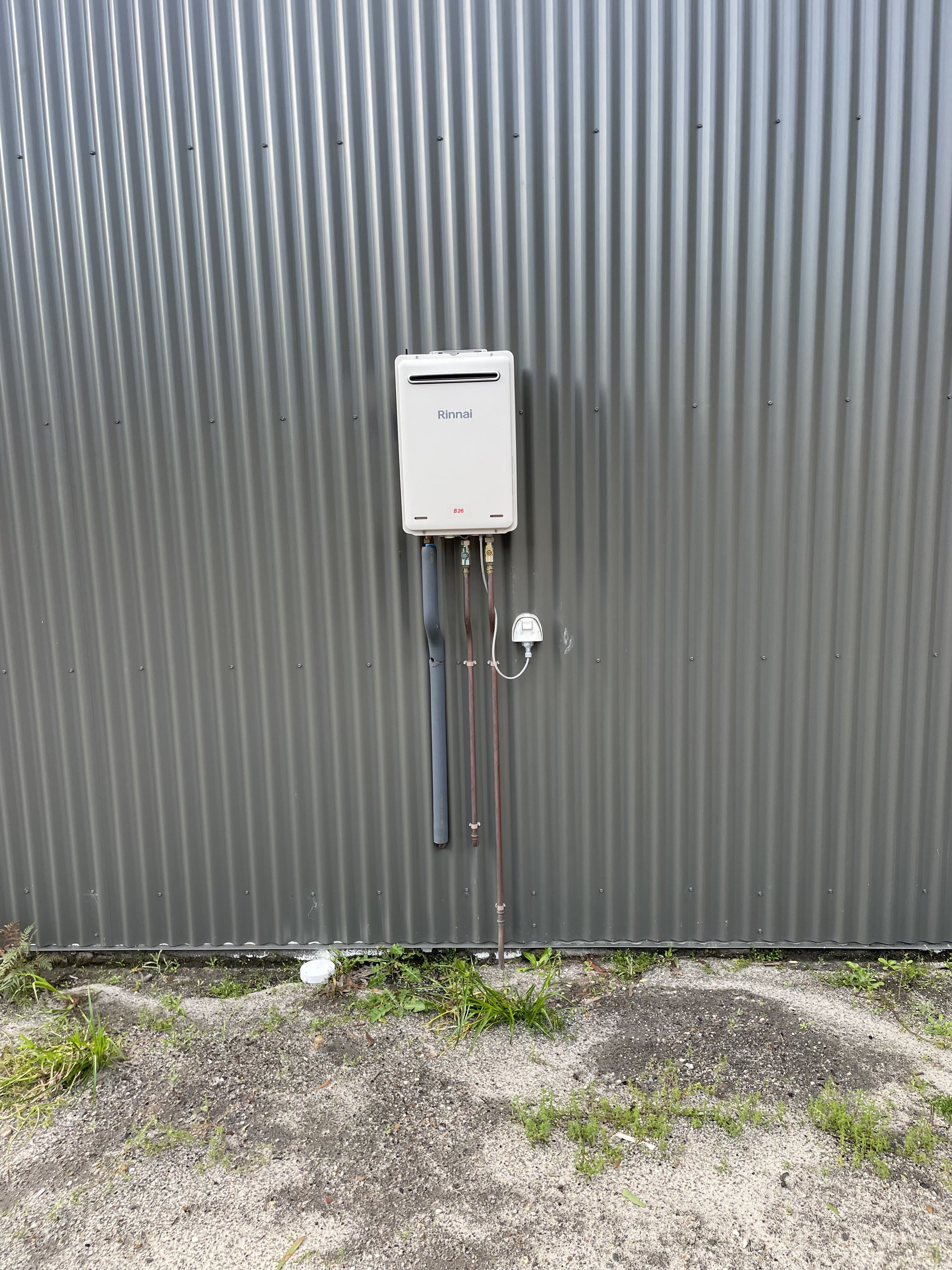 Gas continuous flow hot water unit installed and connected on an external wall