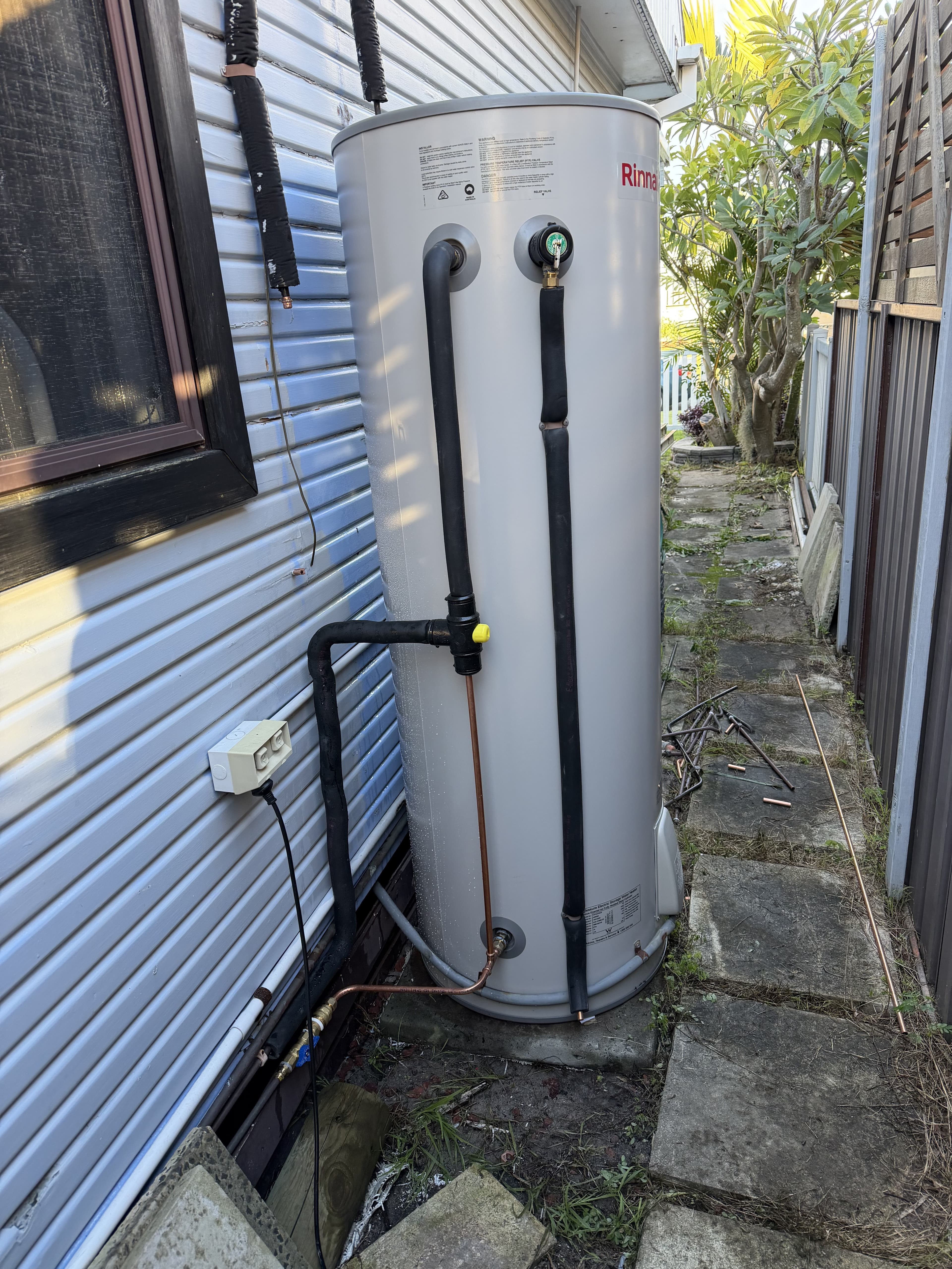 Newly installed hot water storage tank plumbed in against a house wall in Kiama
